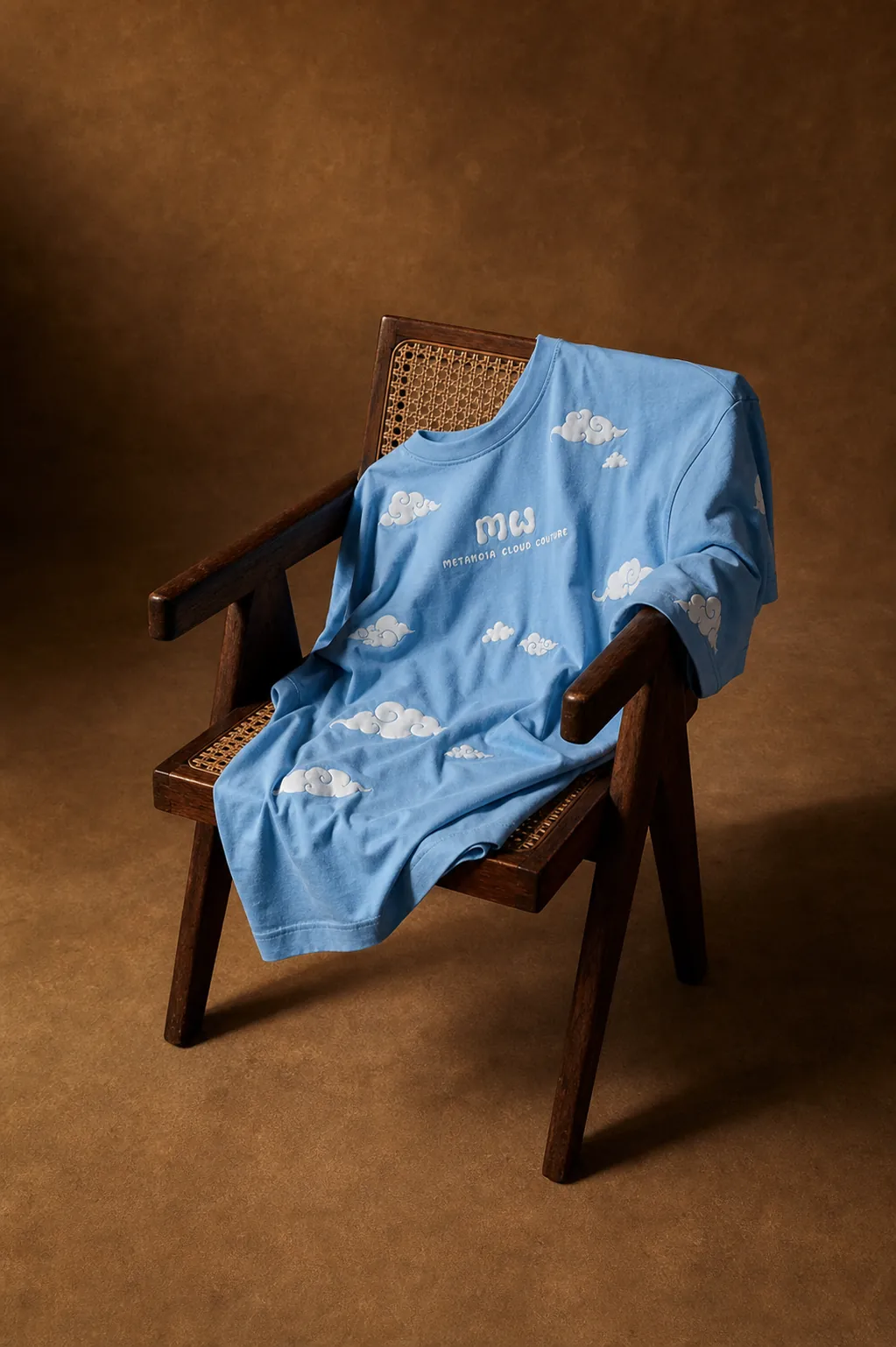 Cloud 9 T-shirt laid flat over a vintage cane chair