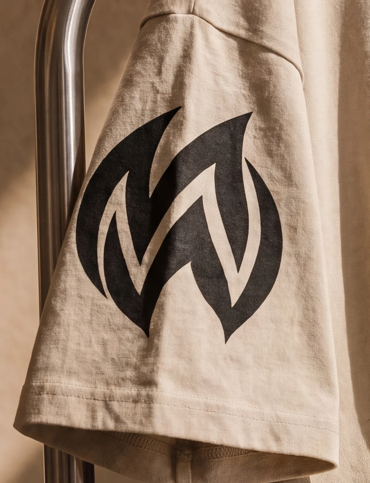 Close on the M monogram printed on the sleeve of the beige tee